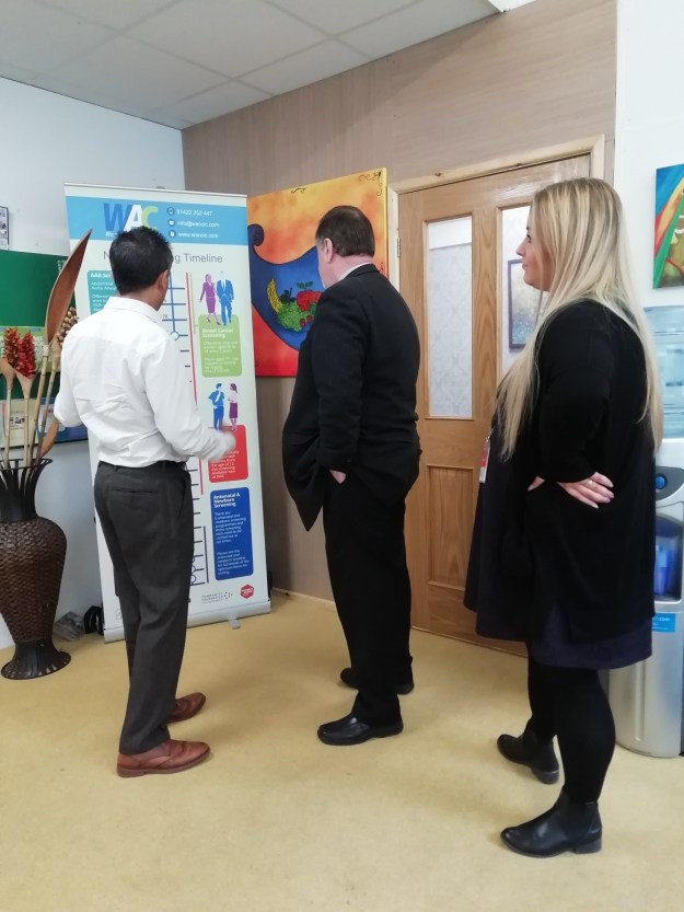 Image of Paige Cowling, Sajeed Mahmood and Mark Burns-Williamson OBE, looking at our NHS Screening Timeline.
